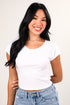 Woman wearing a white t-shirt and blue jeans against a plain background