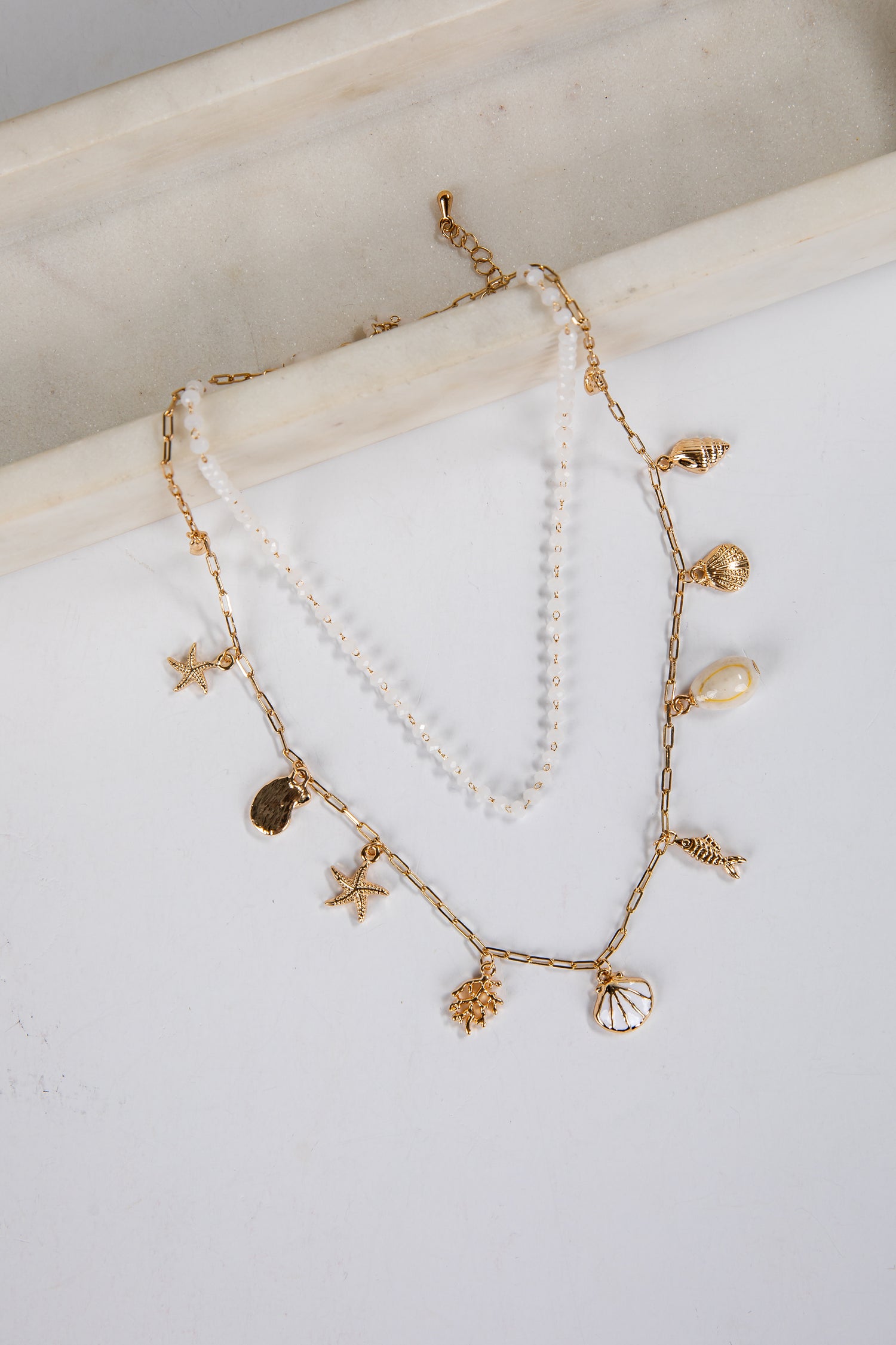 Delicate gold and pearl necklace on a white surface