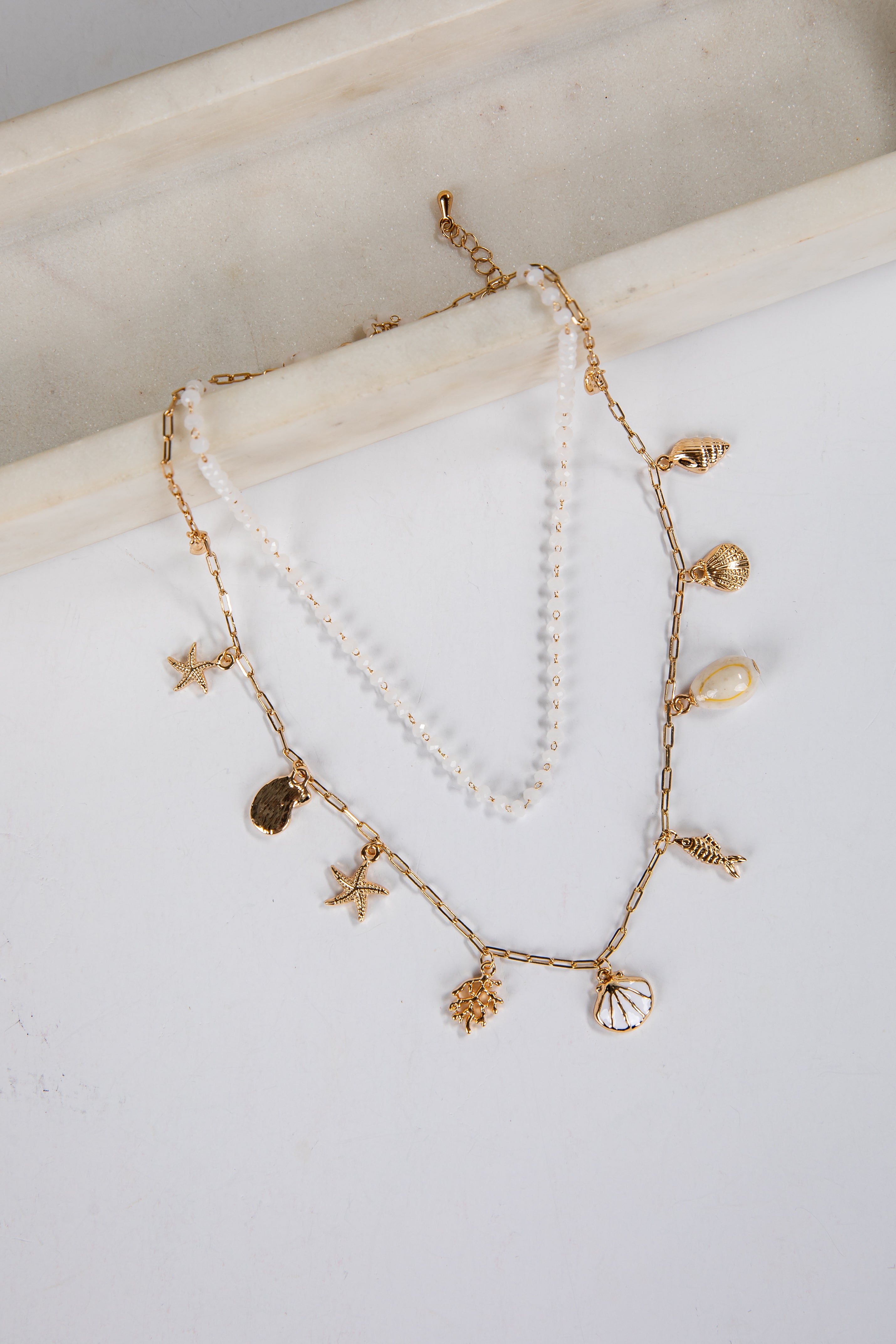 Delicate gold and pearl necklace on a white surface