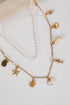 Gold necklace with shell and starfish charms on a white background