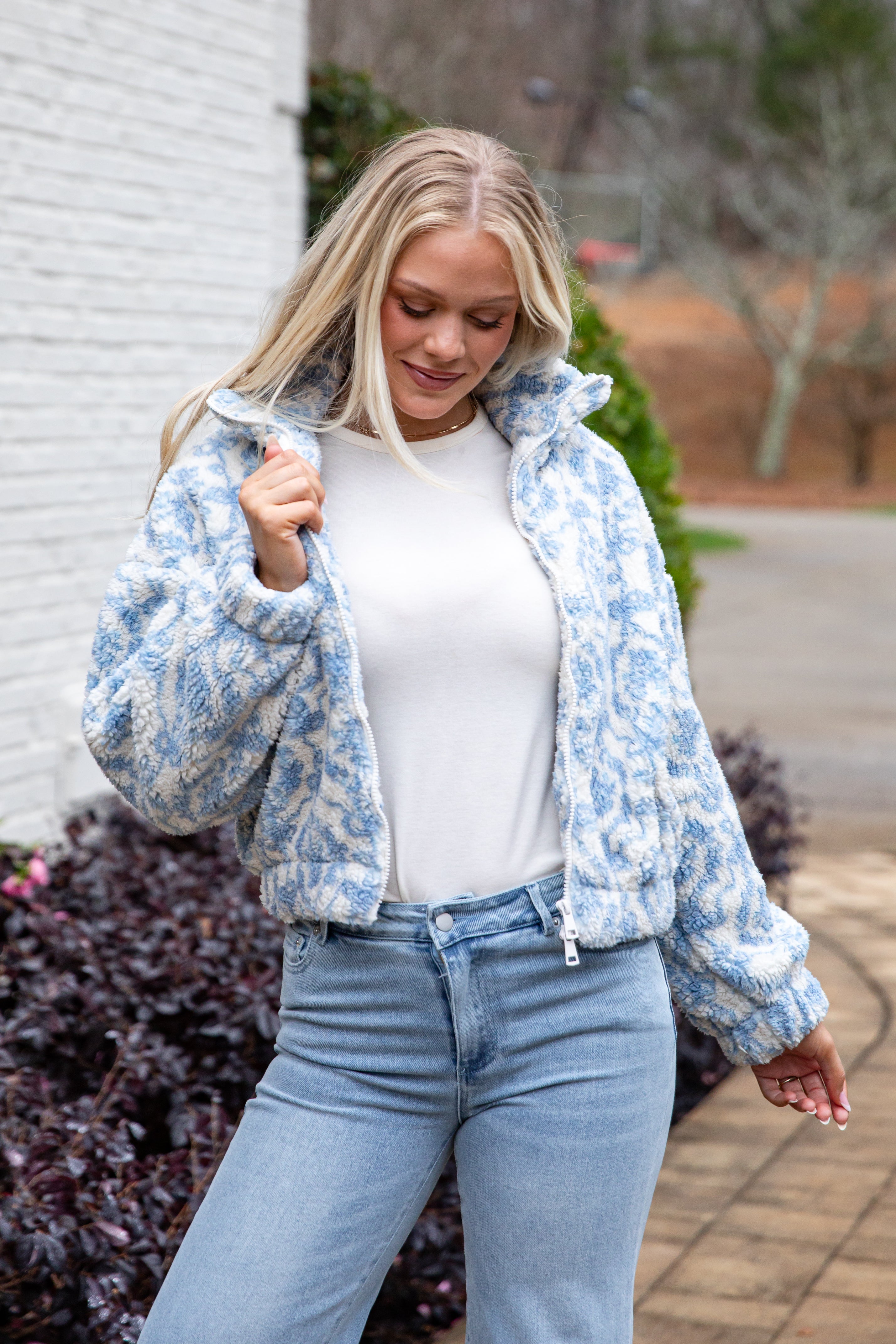 Woman wearing a blue floral jacket and jeans outdoors.