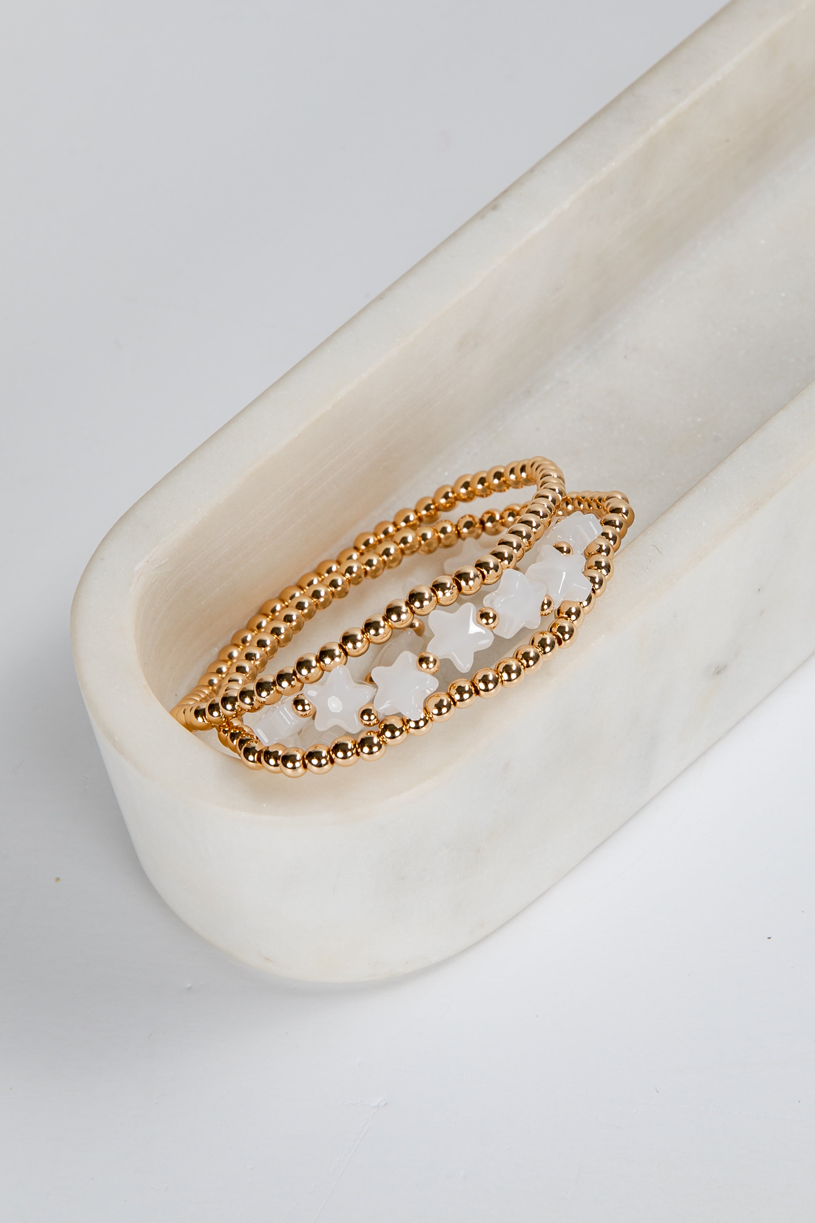 Gold ring with star-shaped stones on a white marble surface