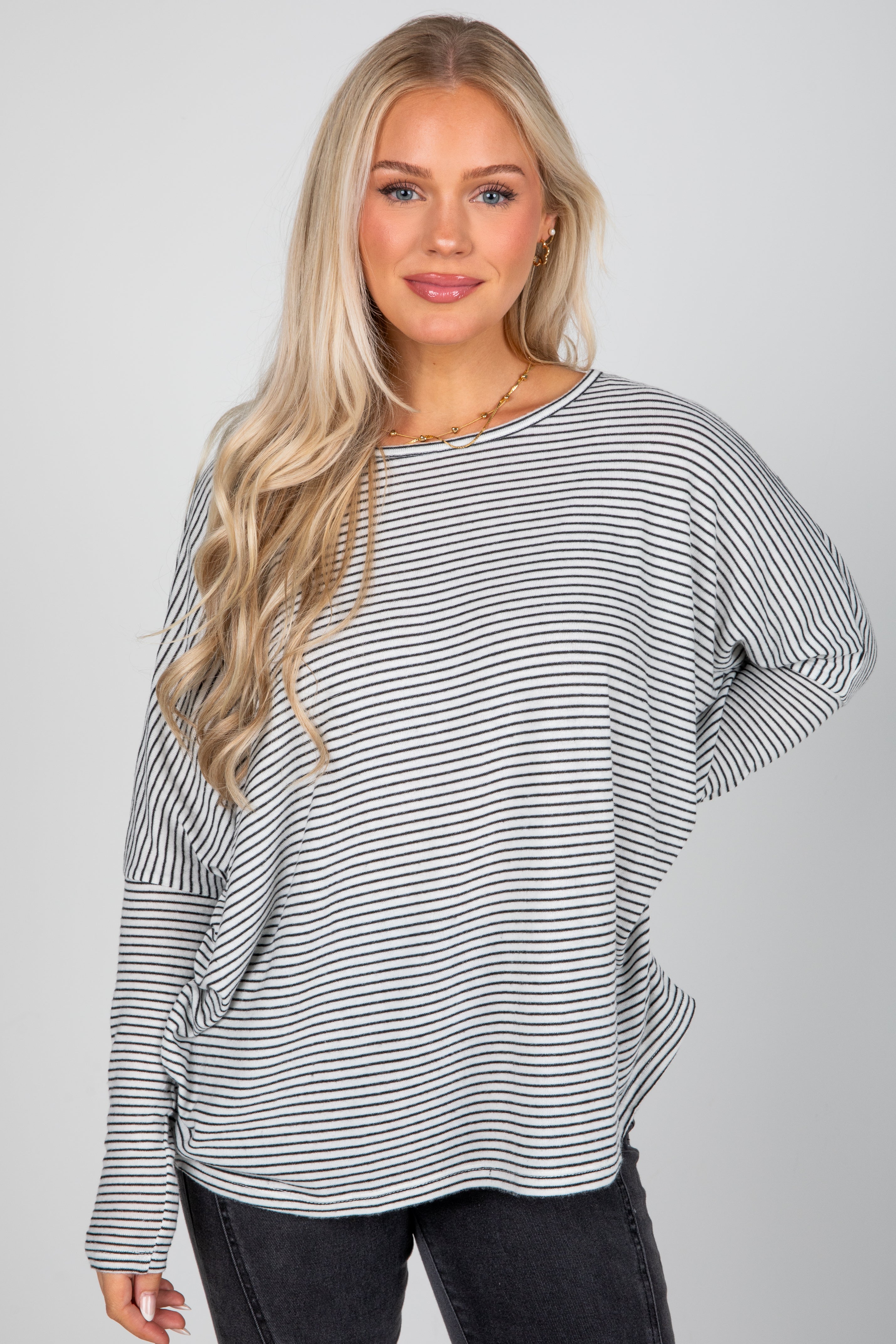 Woman wearing a black and white striped sweater against a plain background