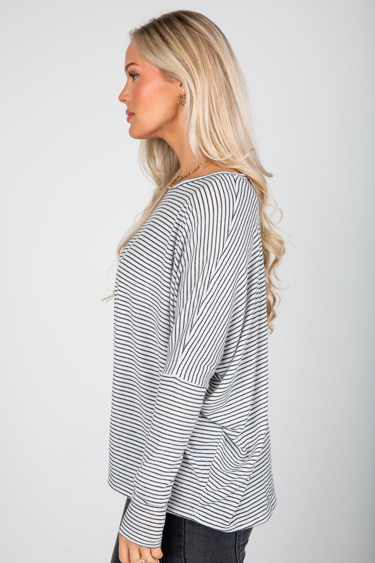 Woman wearing a black and white striped long-sleeve top on a plain background