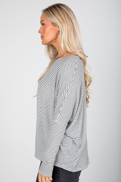 Woman wearing a black and white striped long-sleeve top on a plain background