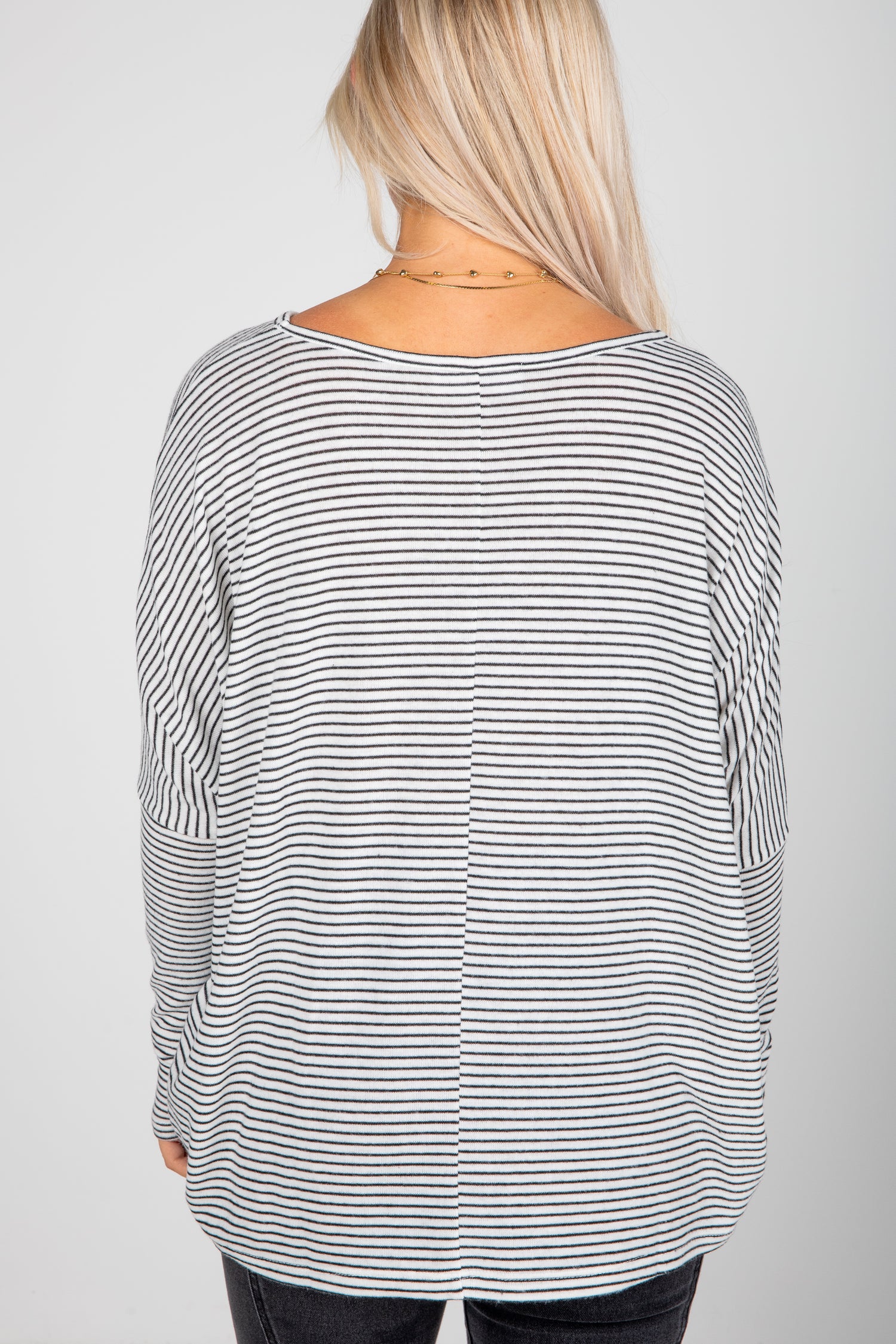 Person wearing a black and white striped long-sleeve top on a plain background