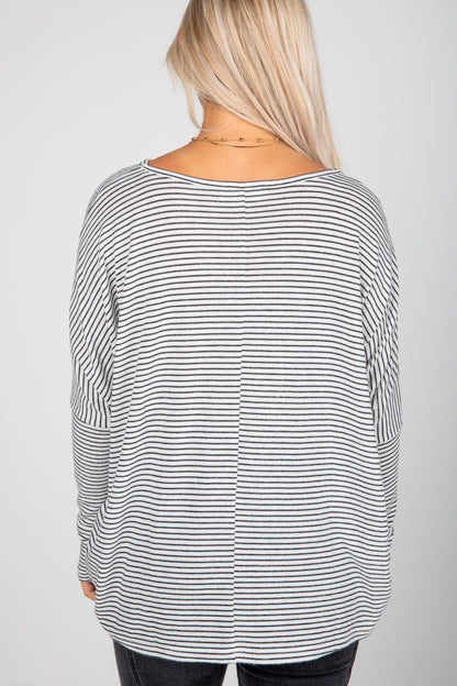 Person wearing a black and white striped long-sleeve top on a plain background