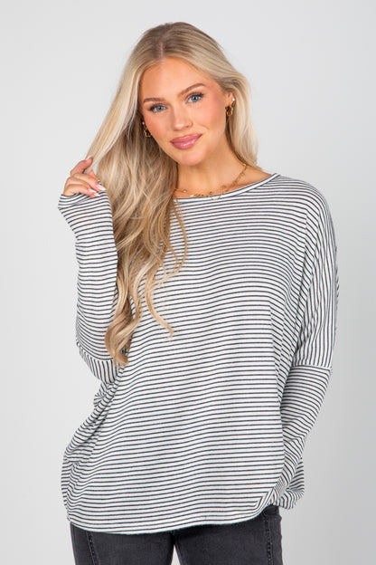 Woman wearing a black and white striped long-sleeve top on a plain background