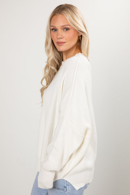 Woman wearing a white sweater against a plain background