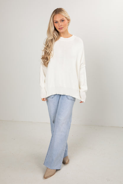 Woman wearing a white blouse and light blue jeans on a plain background