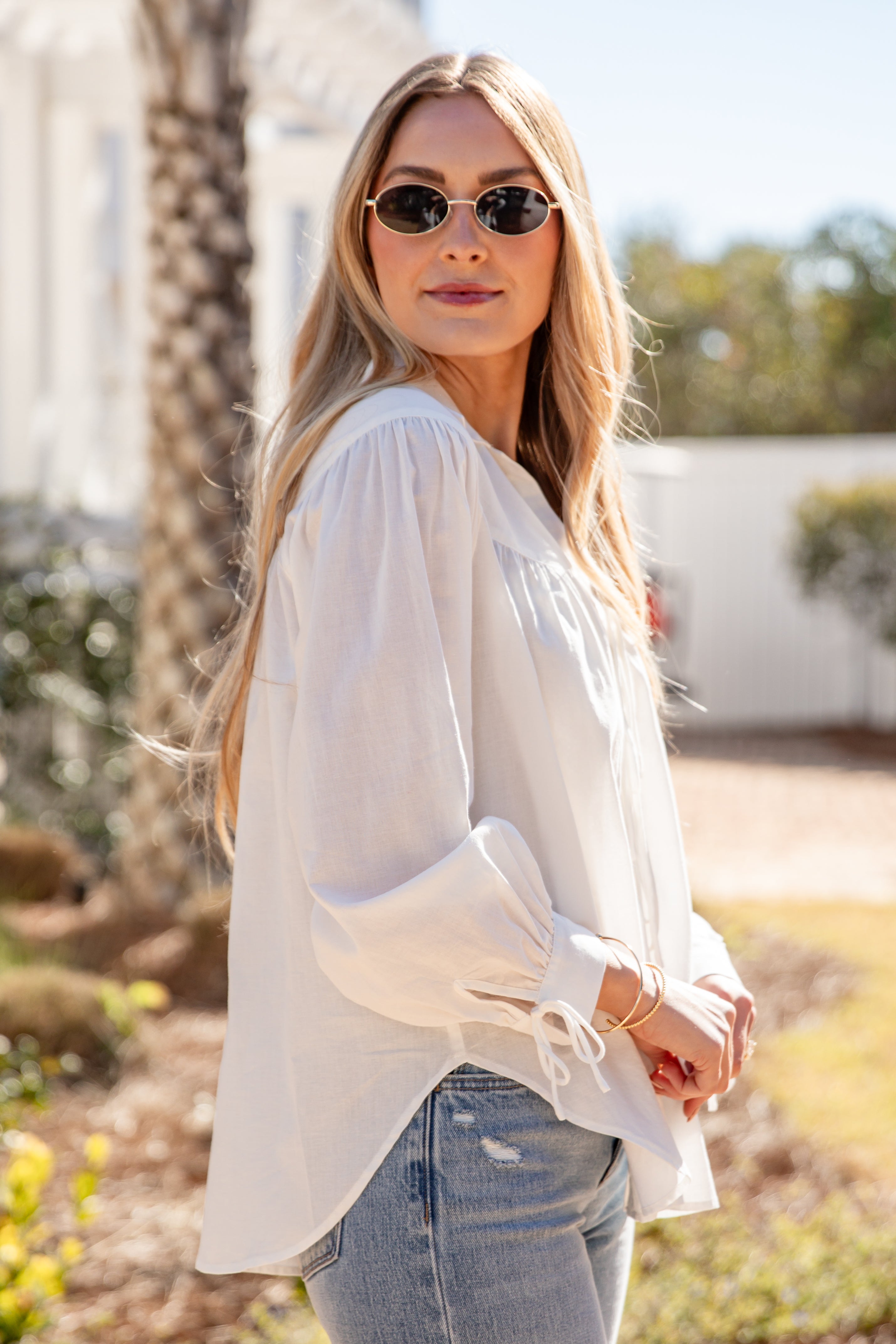 Woman wearing a white blouse and sunglasses outdoors