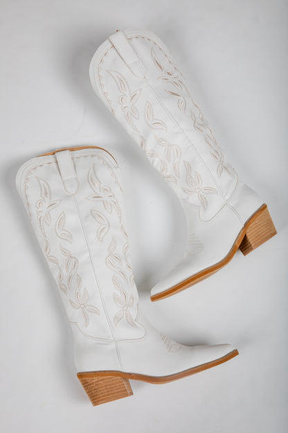 White cowboy boots with brown soles on a light gray background