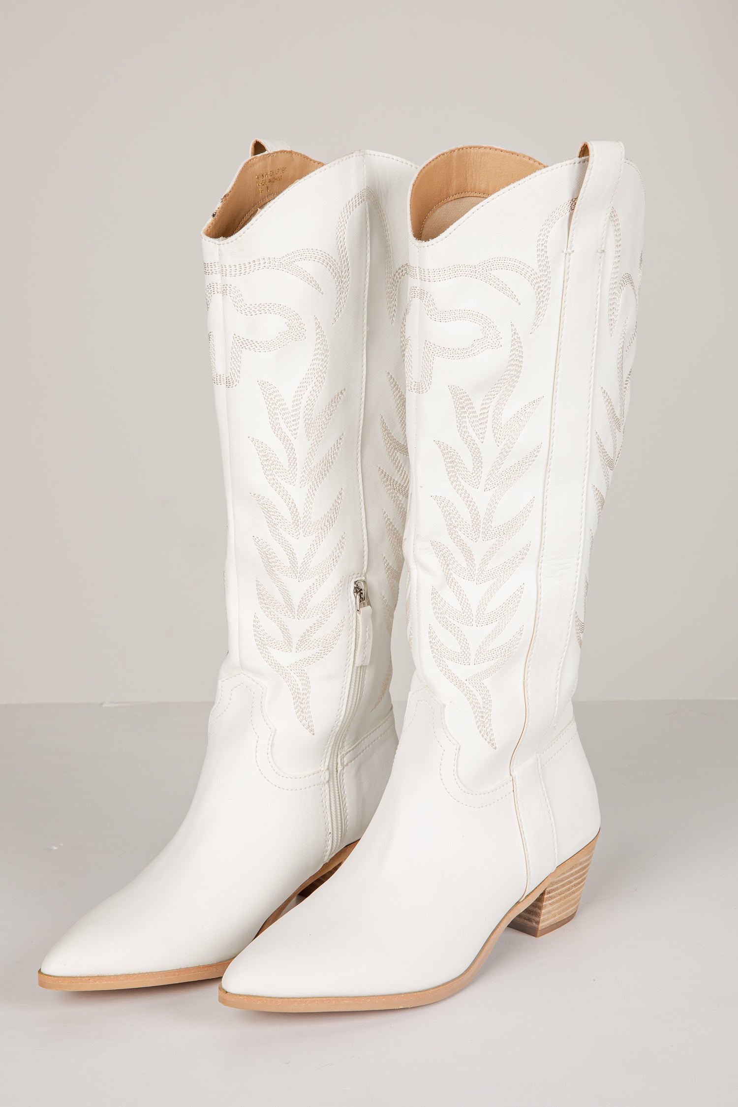 White quilted knee-high boots on a light gray background
