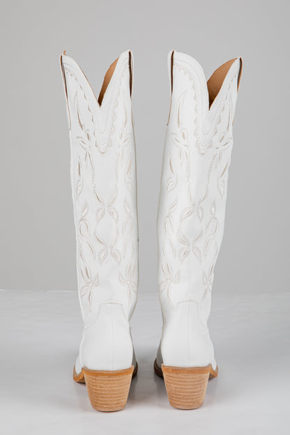 White cowboy boots with brown soles on a gray background
