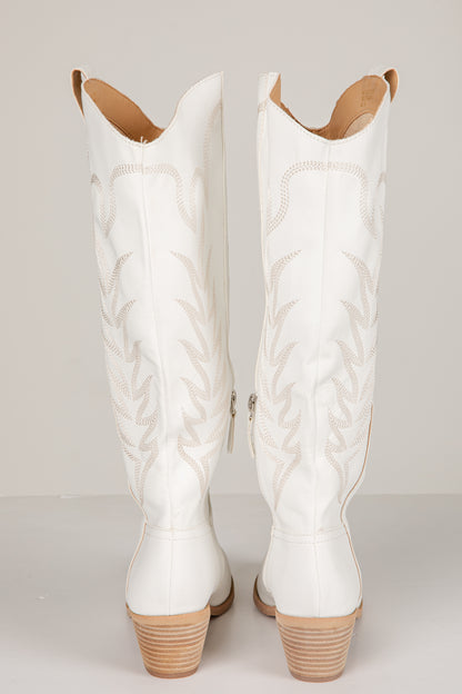 Pair of white quilted cowboy boots on a light gray background