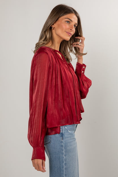 Woman wearing a red blouse and blue jeans against a plain background