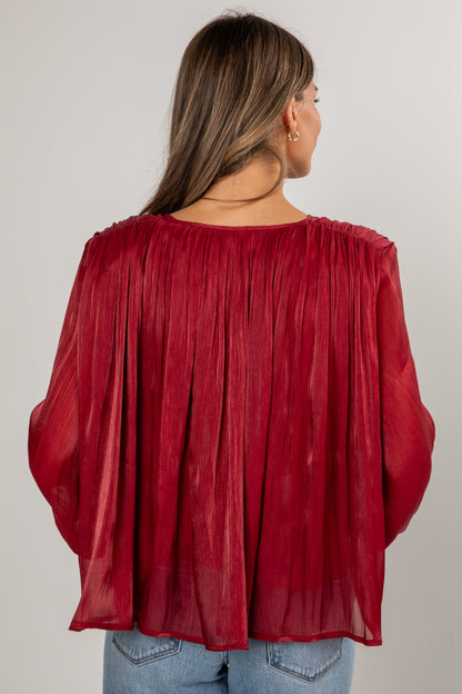 Red sheer blouse worn by a person on a plain background