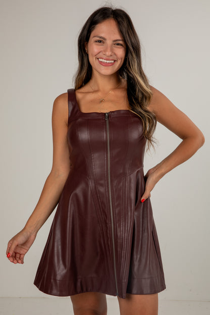 Woman wearing a brown leather dress against a plain background