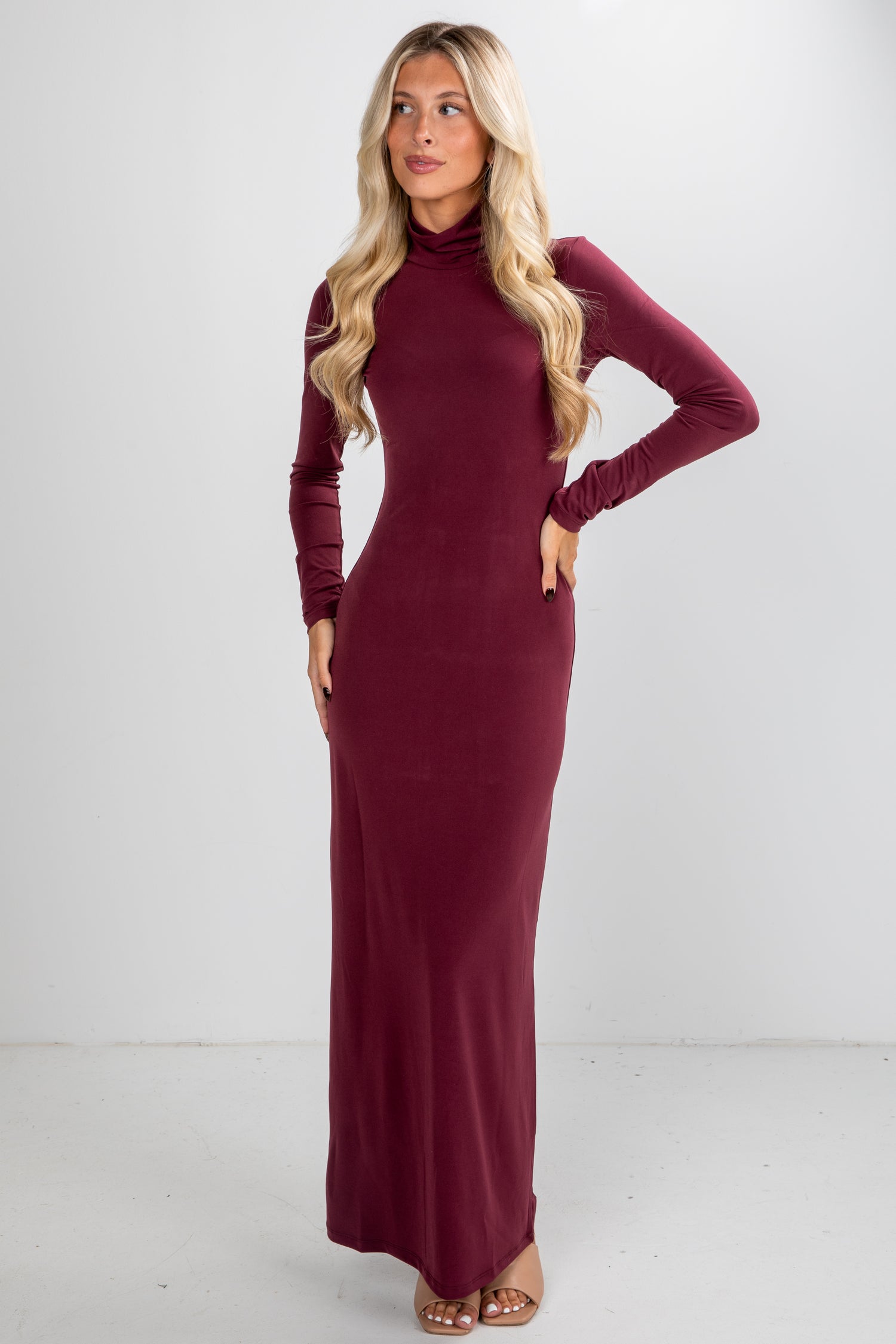 Woman wearing a burgundy long-sleeve dress against a white background
