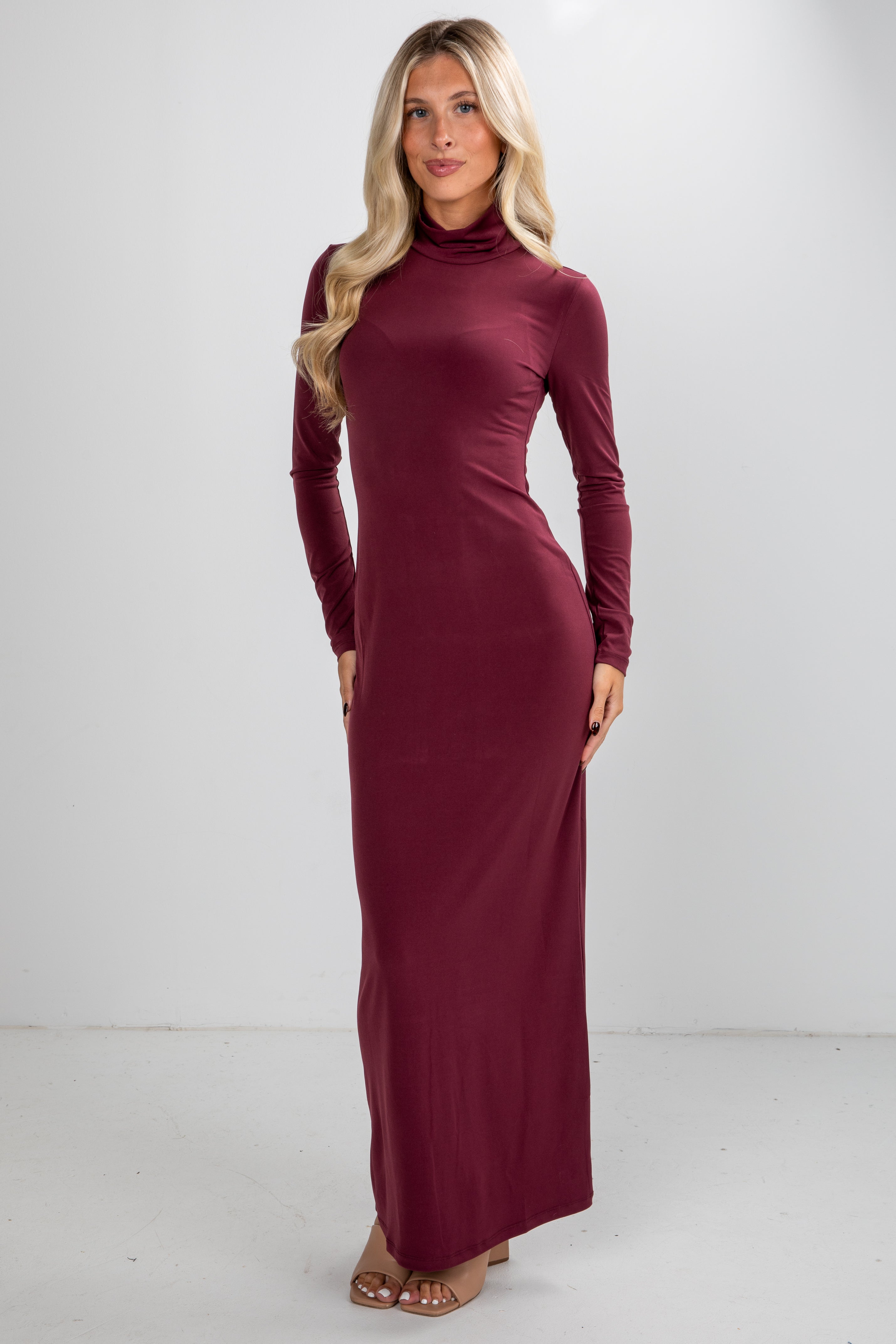 Woman wearing a burgundy long-sleeve dress against a white background
