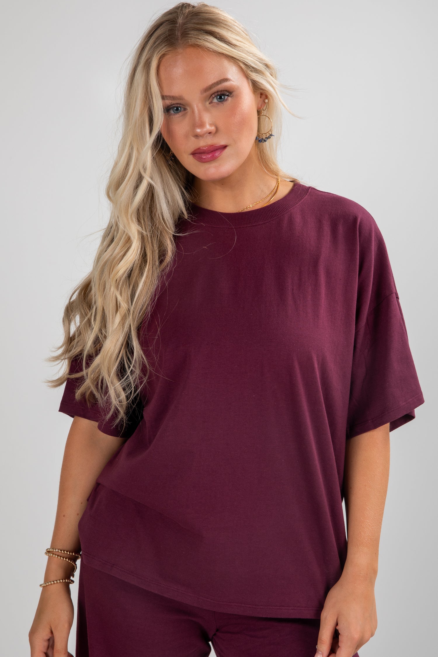 Woman wearing a burgundy oversized t-shirt against a plain background