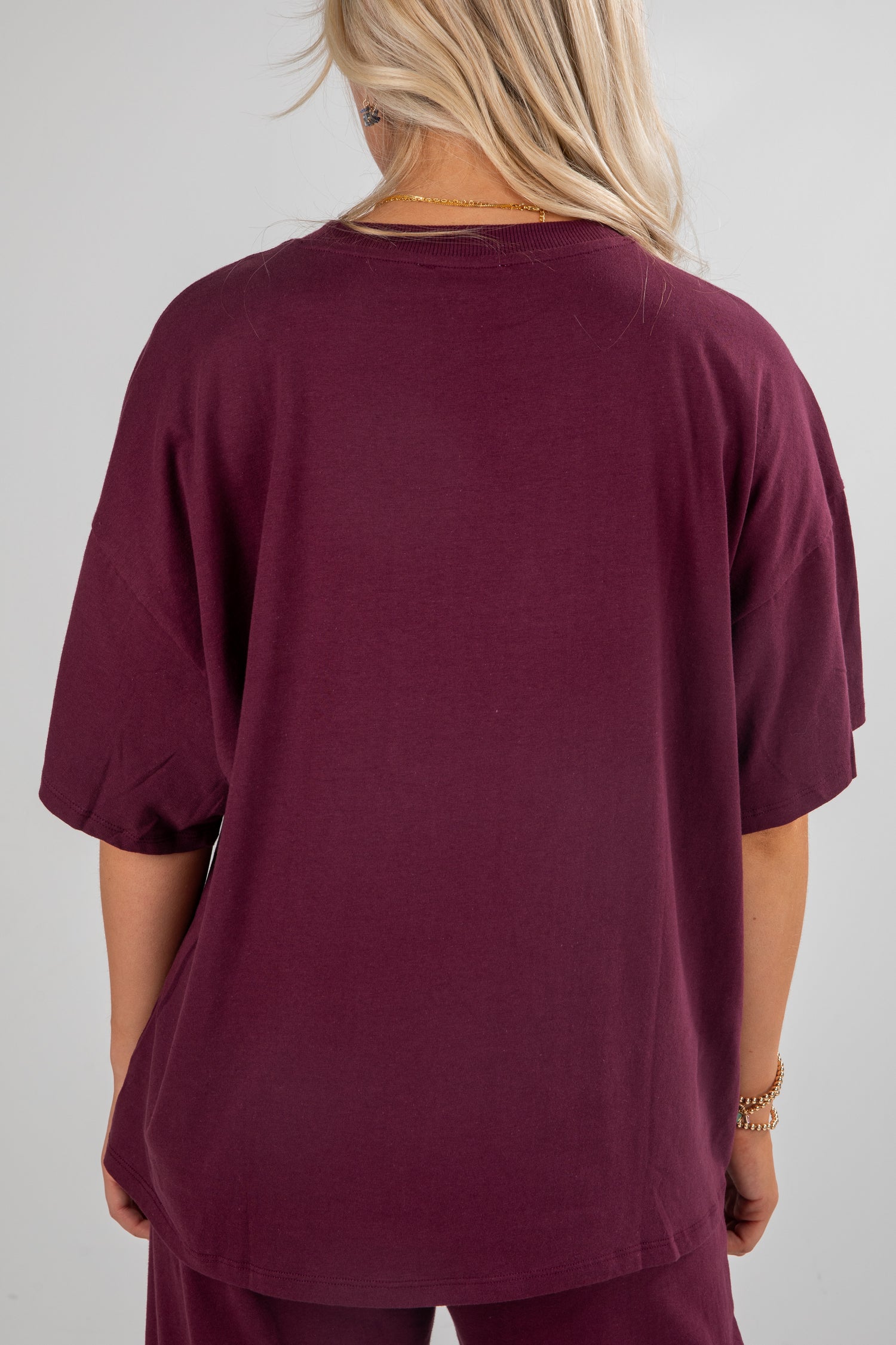 Person wearing a burgundy oversized t-shirt on a plain background