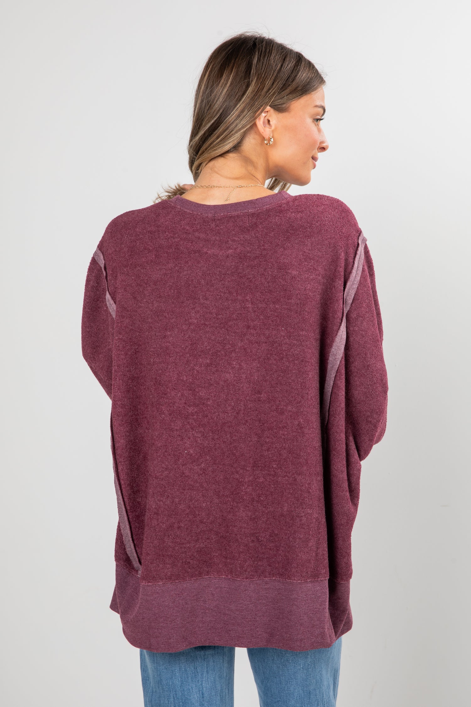Woman wearing a maroon sweater with a plain background