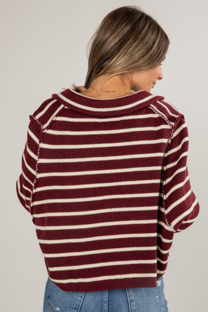 Woman wearing a maroon and white striped sweater on a plain background
