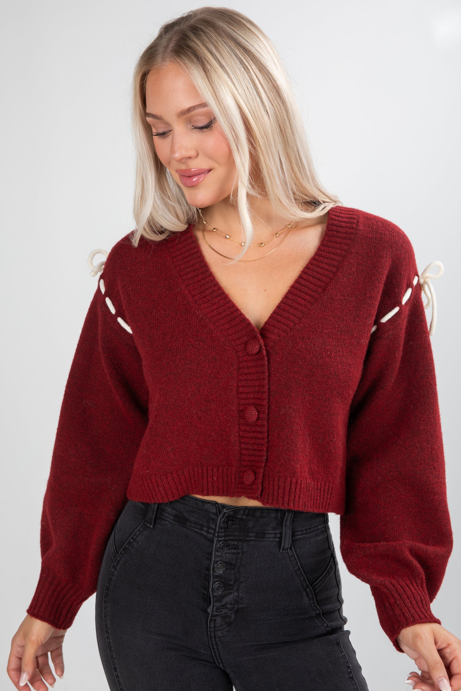 Woman wearing a red sweater with white accents on a plain background