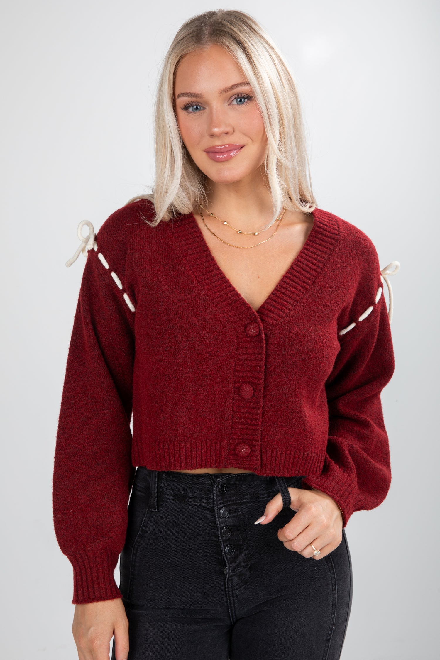 Woman wearing a red cardigan with white trim on a plain background