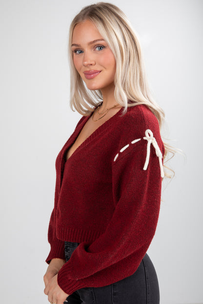 Woman wearing a red sweater with white accents on a plain background