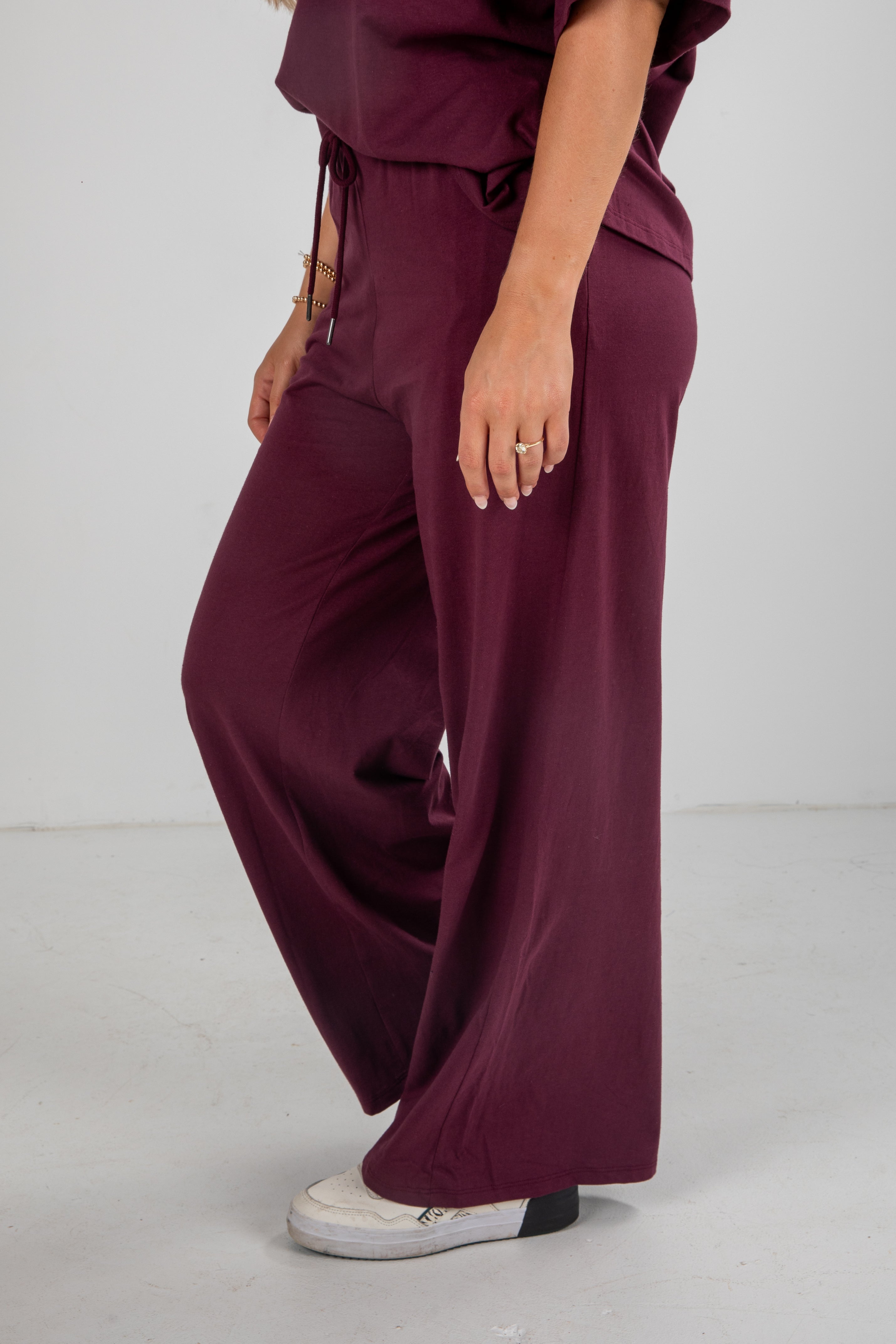 Person wearing burgundy wide-leg pants and a matching top on a white background