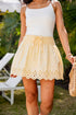 Woman wearing a white tank top and yellow lace skirt outdoors.
