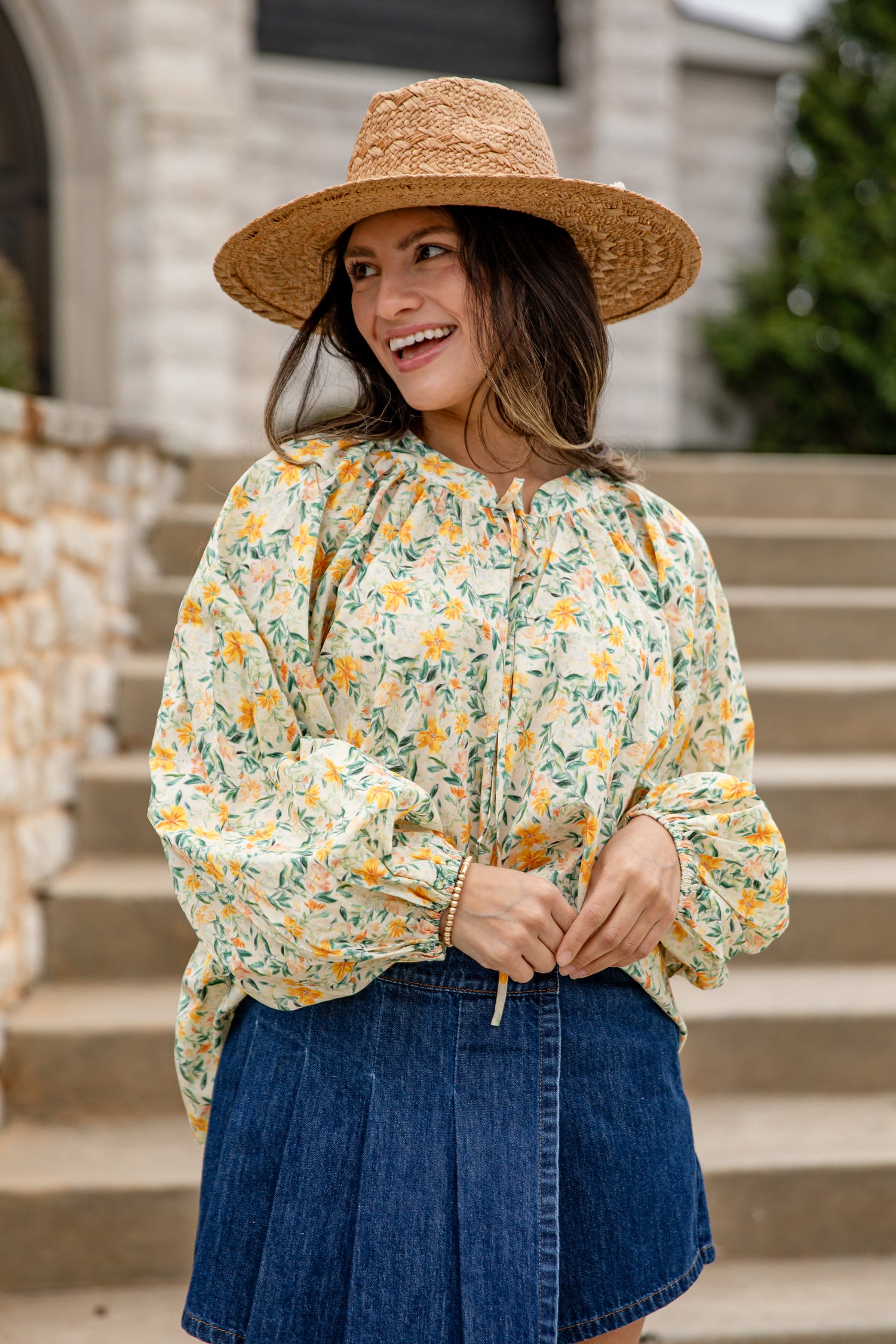 Woman wearing a floral blouse and straw hat outdoors