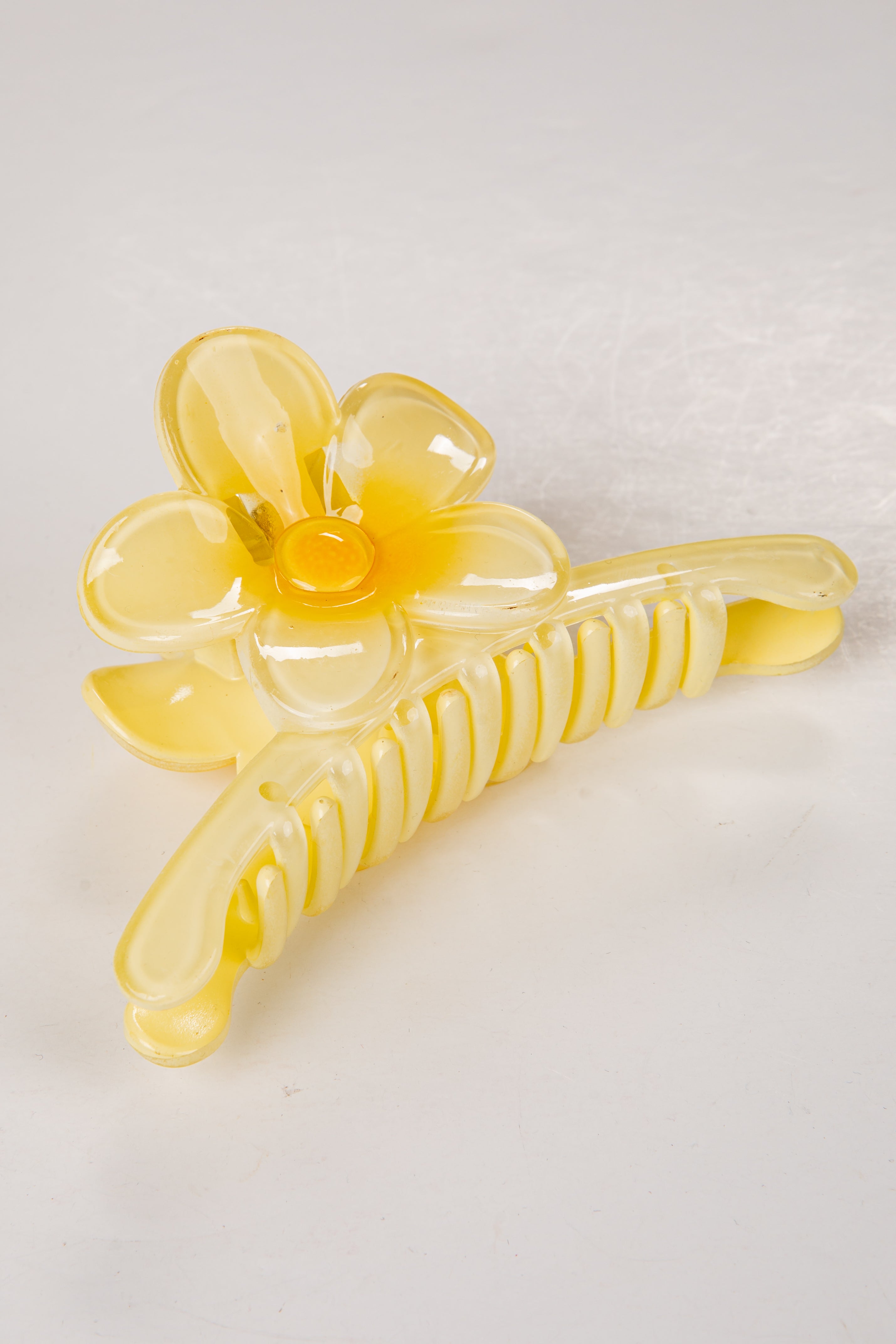 Yellow flower-shaped hair clip on a light gray background