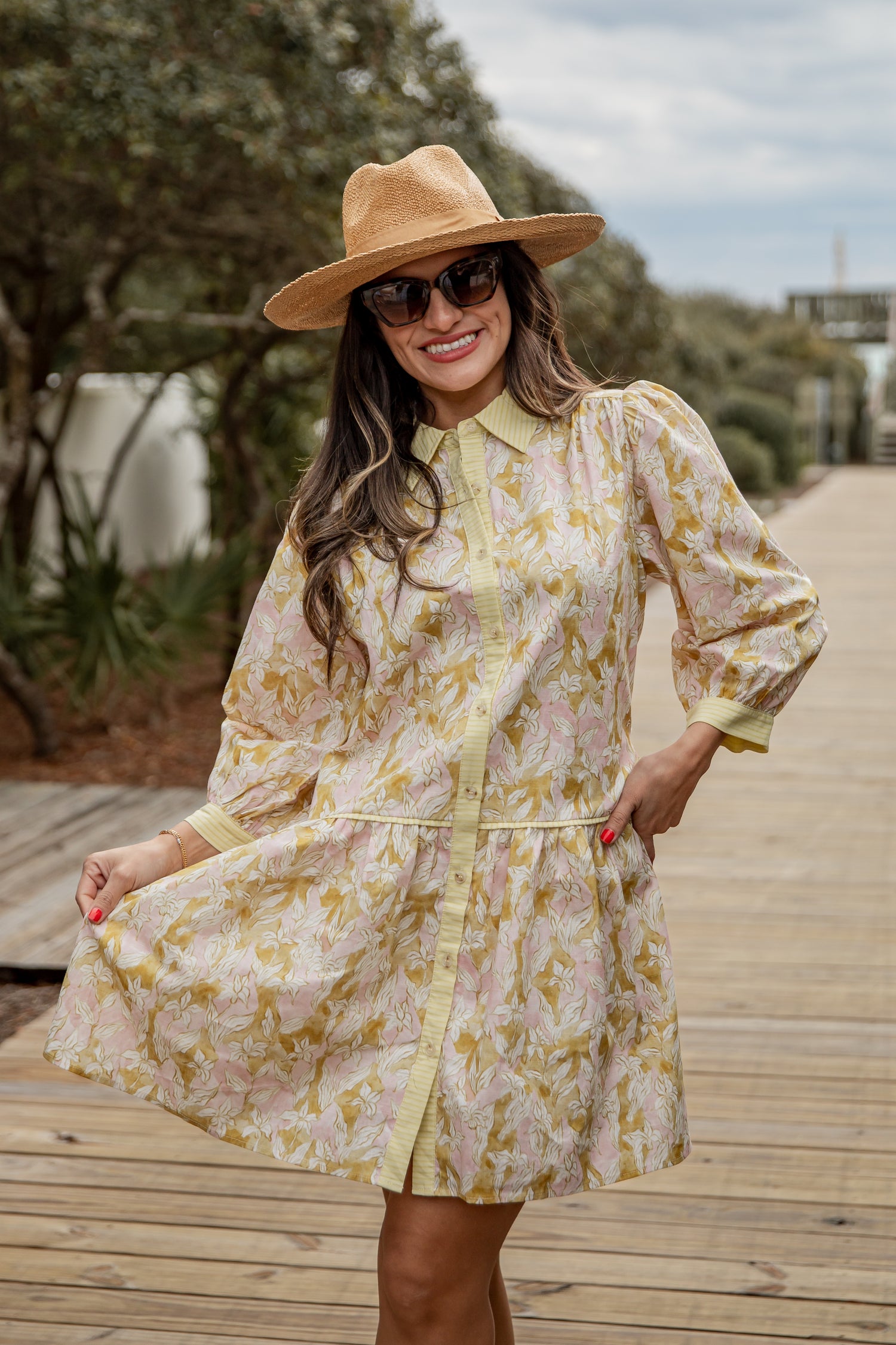 Woman wearing a floral dress and hat on a wooden pathway