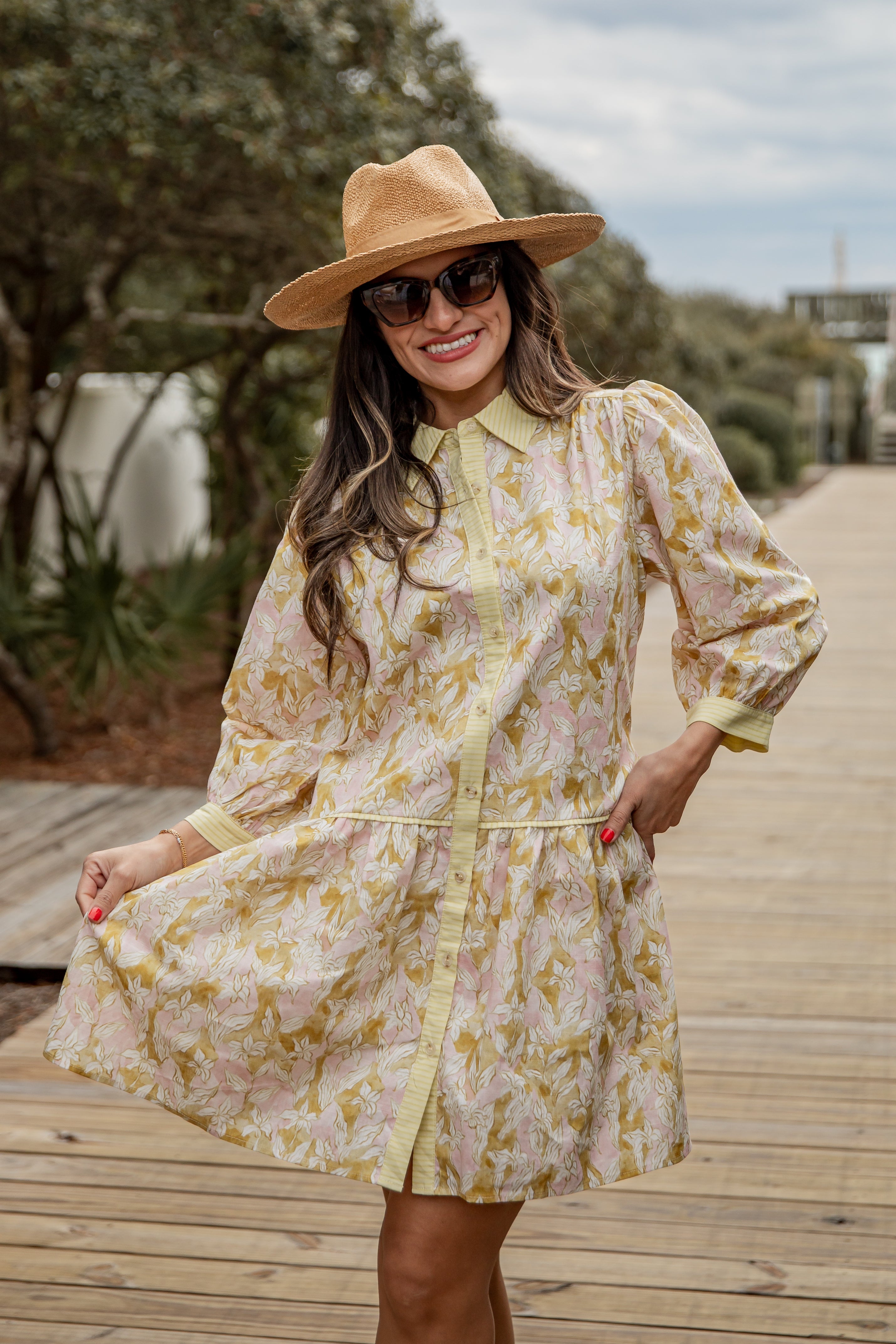 Woman wearing a floral dress and hat on a wooden pathway