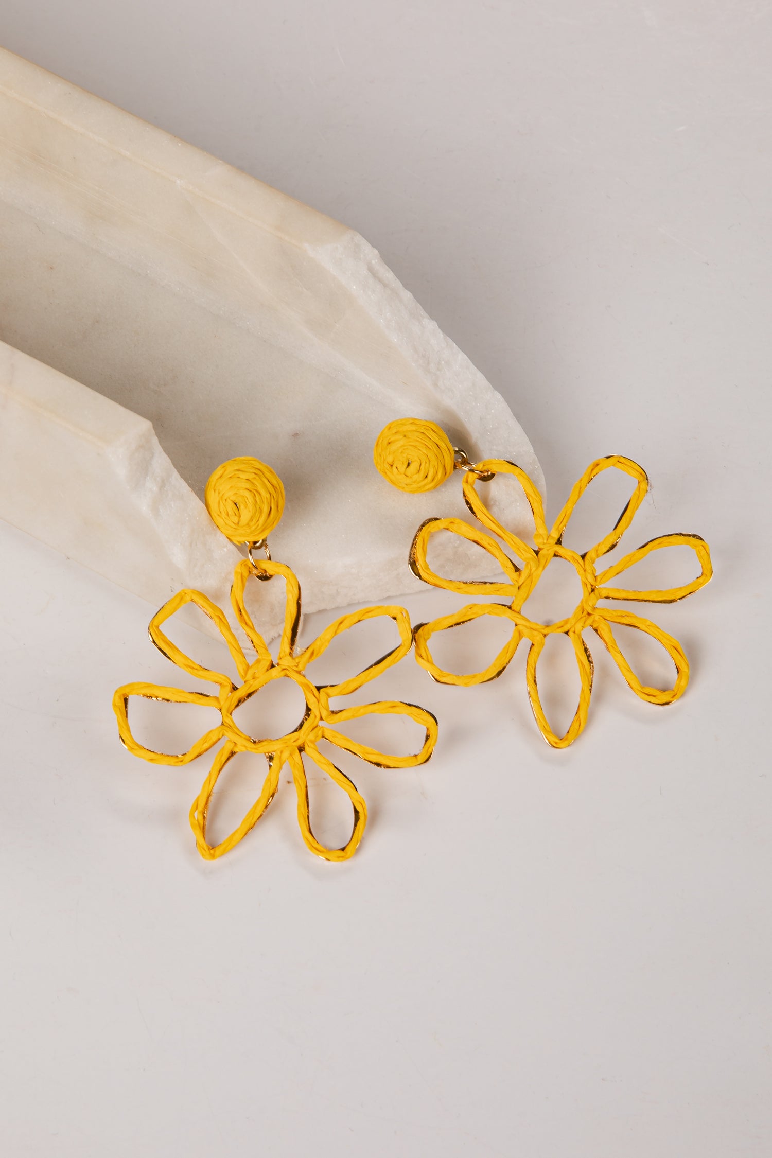 Yellow flower-shaped earrings on a light gray background