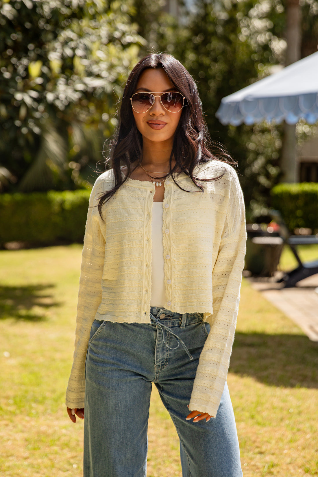 Woman wearing sunglasses and a light-colored jacket outdoors