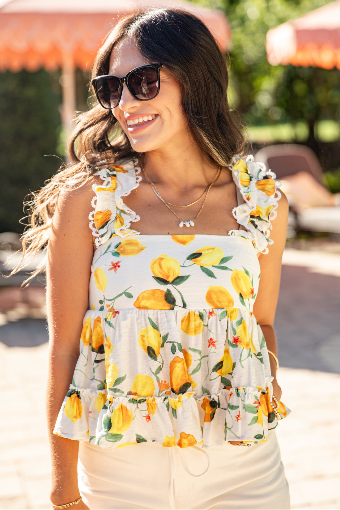 Woman wearing a lemon-patterned dress with sunglasses outdoors.