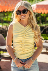 Woman wearing sunglasses and a yellow top outdoors with orange umbrellas in the background