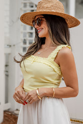 Woman wearing a yellow top and straw hat outdoors