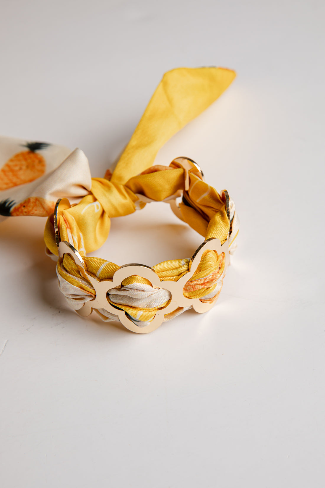 Yellow and beige headband with a decorative bow on a light gray background