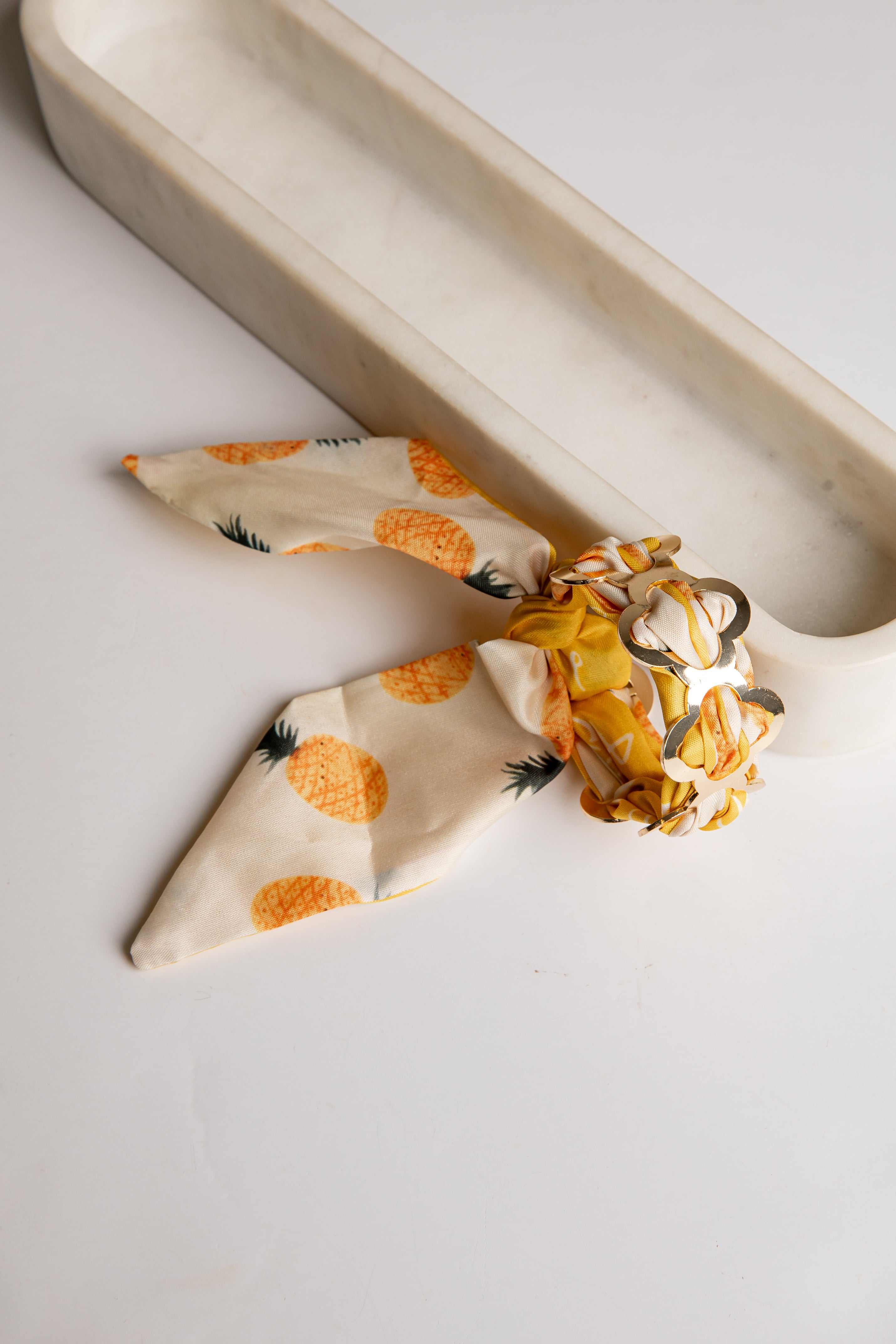 Bandana bracelet including a tie on a light surface with a neutral background