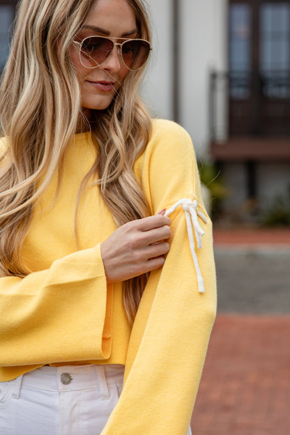 Woman wearing a yellow outfit with sunglasses outdoors