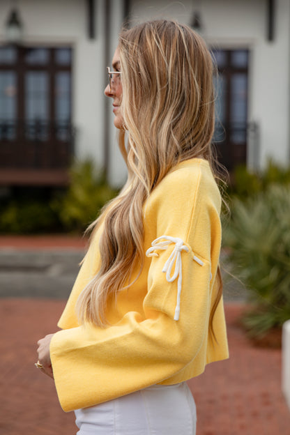 Woman wearing a yellow hoodie with white drawstrings outdoors.