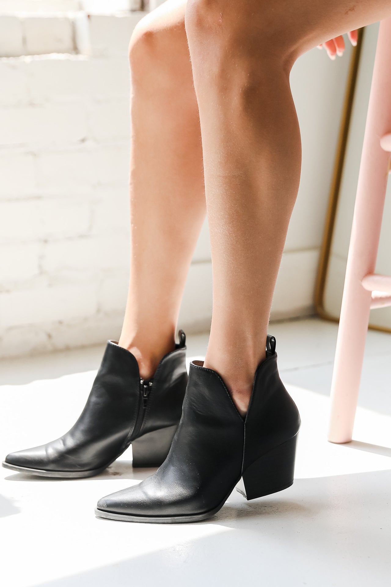 model wearing black faux leather pointed toe heeled ankle booties