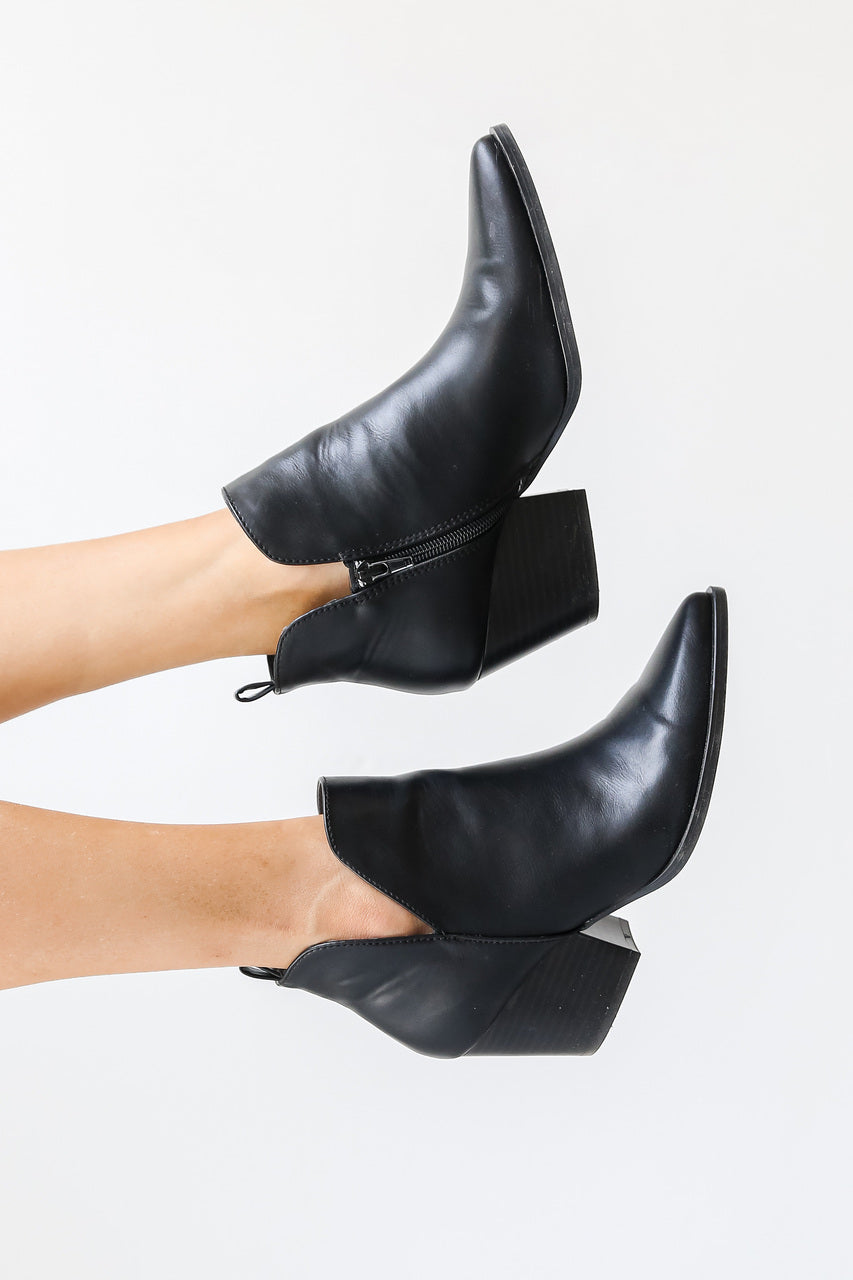 model wearing black faux leather pointed toe ankle booties with cutout sides