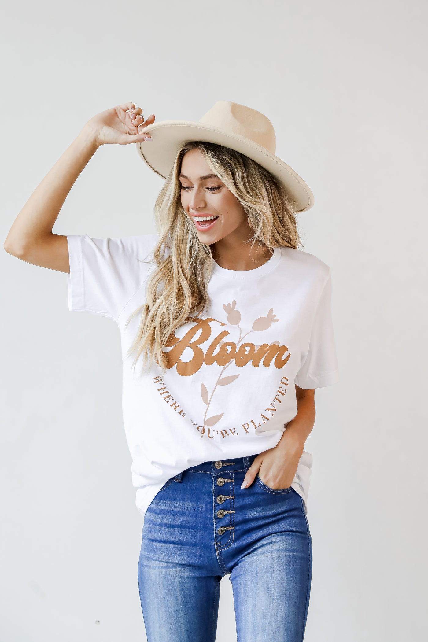 This comfy tee is designed with a soft and stretchy knit. It features a crew neckline, short sleeves, a relaxed fit, and the words "Bloom Where You're Planted" on the front.