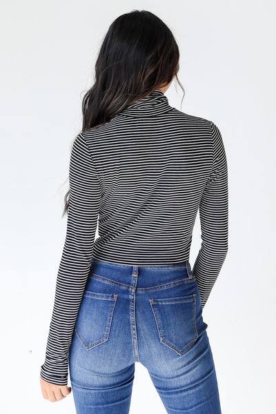 model wearing black and white striped mock neck basic top back view